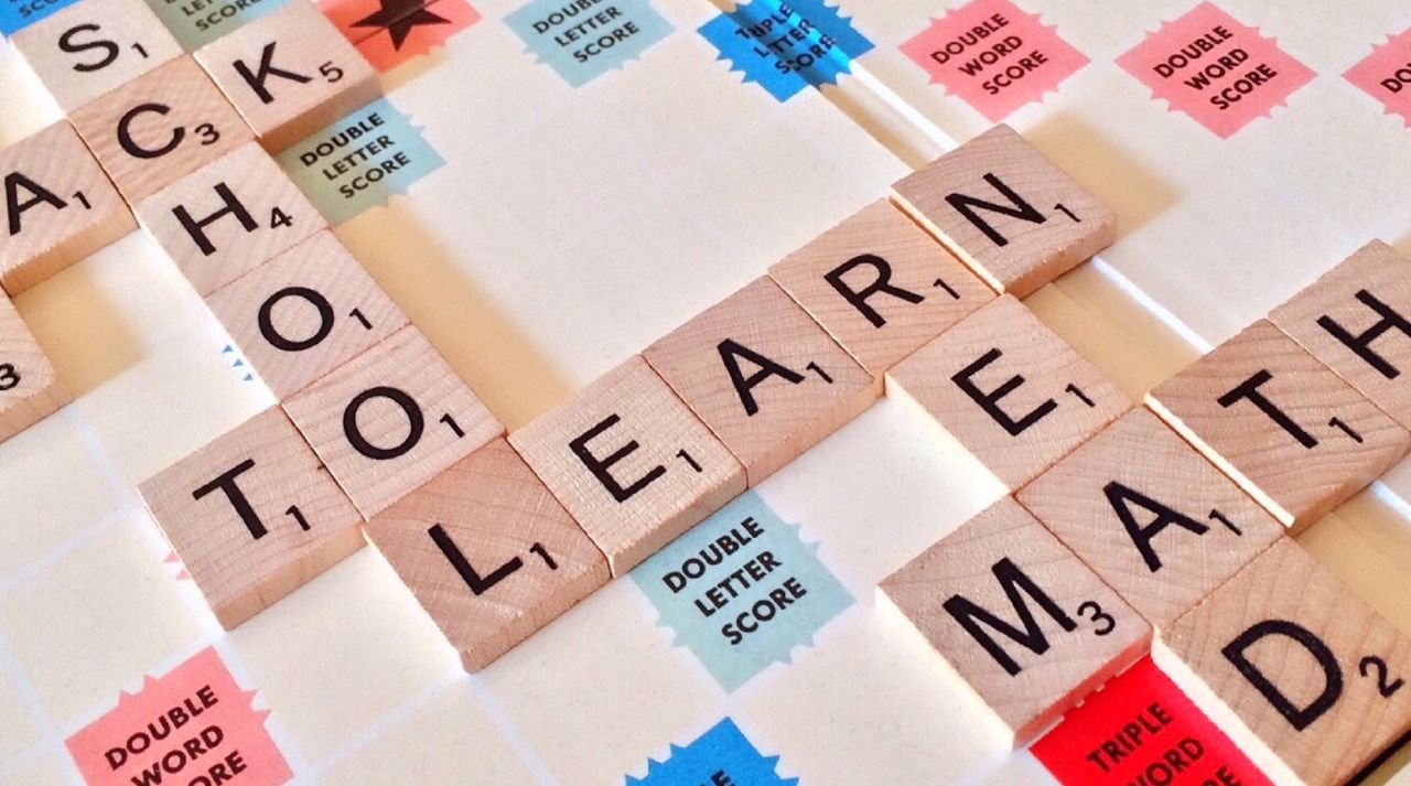 The Art of Drawing Readers In: Your attractive post title goes here Close-up of Scrabble tiles forming words related to education and school.