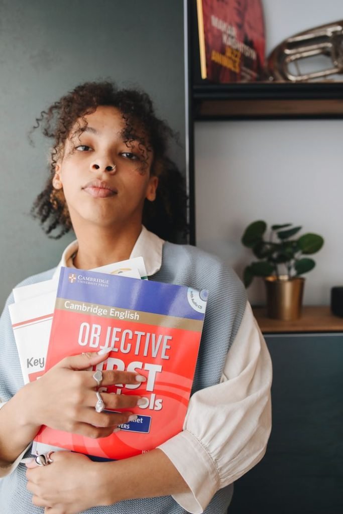 Student holding English study guides in an indoor setting, showcasing pensive expression.